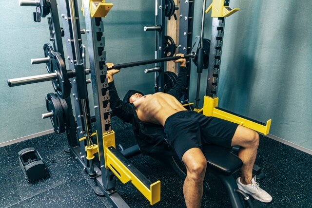 ジムのスミスマシンでベンチプレスをする男性