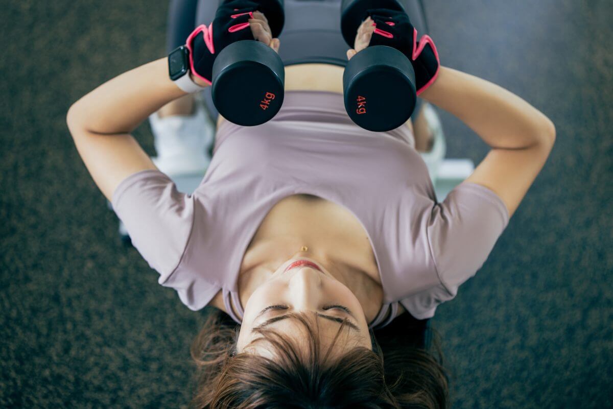 ジムでダンベルを使ってダイエットする女性