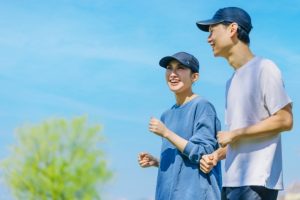 青空の下でウォーキングをする笑顔の男女