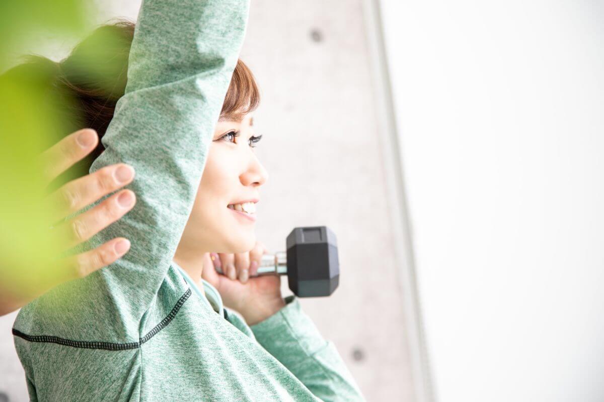 パーソナルジムでダンベルトレーニングをする女性