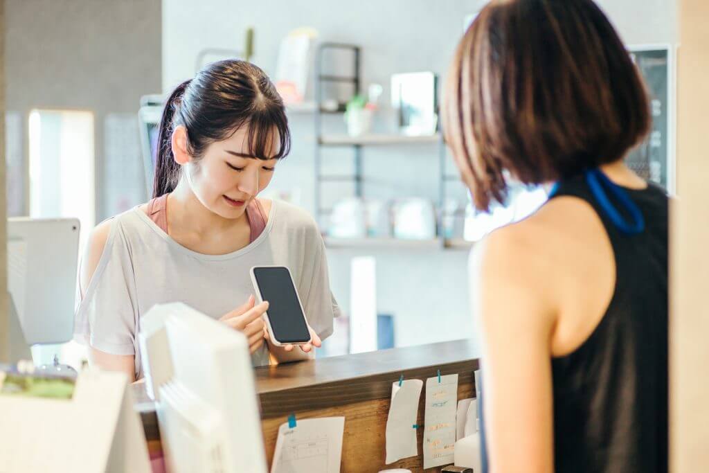 ジムの受付で会員証を出す女性