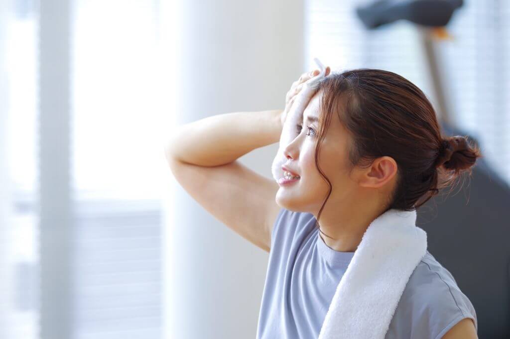 ジムでタオルで汗を拭く女性