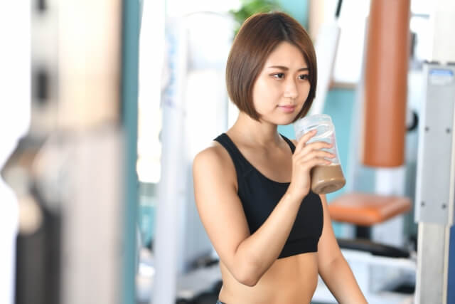 ジムでプロテインを飲む女性