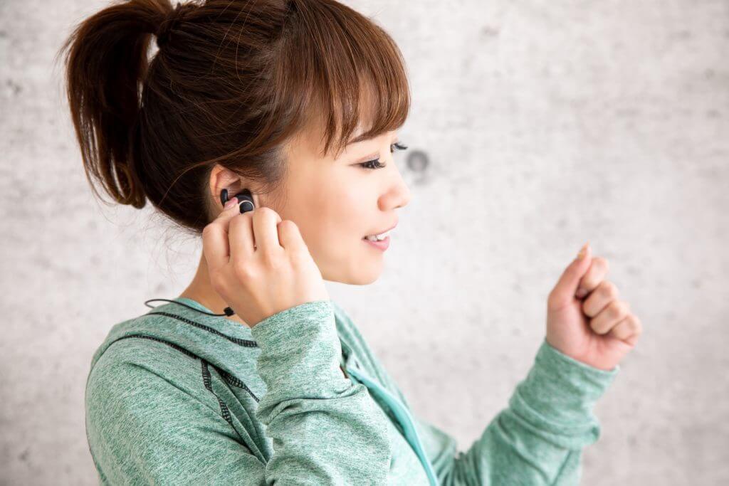 イヤフォンをつけてトレーニングの準備をする女性