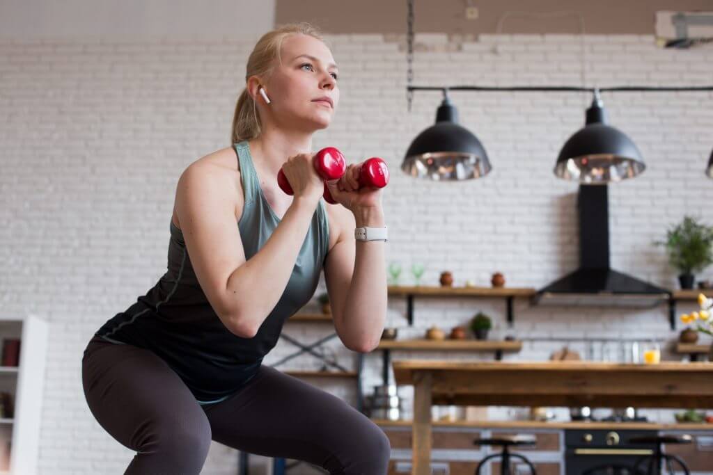 家でダンベルトレーニングをする女性
