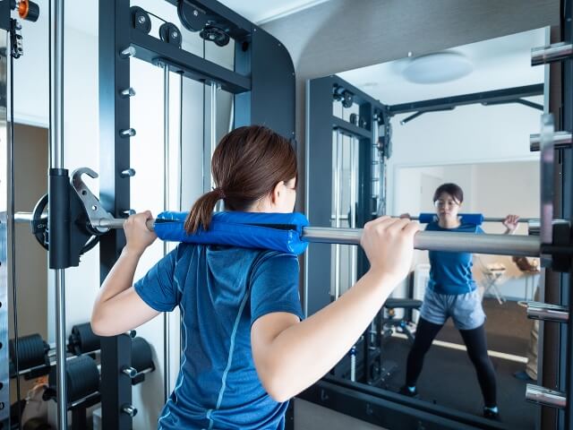 パワーラックでスクワットする女性