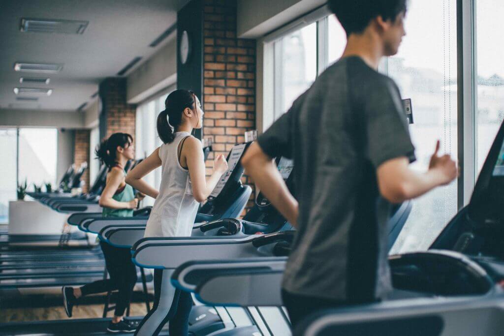 ジムのランニングマシンで走る人たち