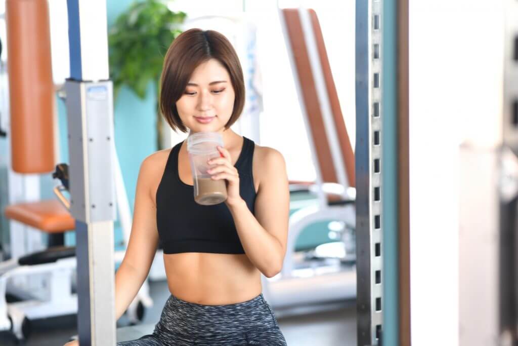 ジムでプロテインを飲む女性